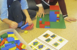 En elev sammen med en lærer setter sammen lego.